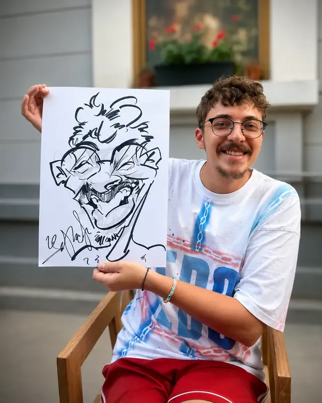 Un tânăr în tricou alb își ține caricatura lângă față