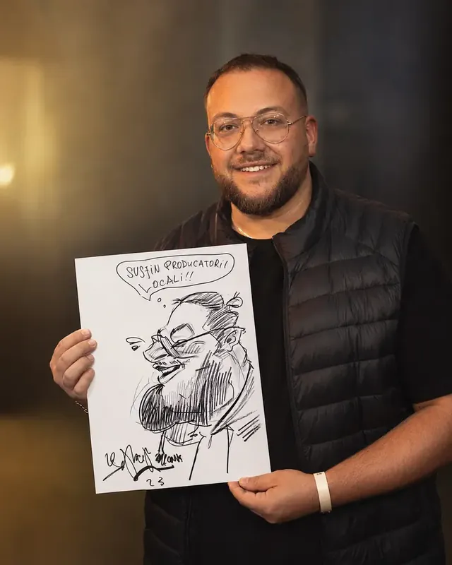 Un bărbat cu barbă își ține caricatura cu un balon de vorbă