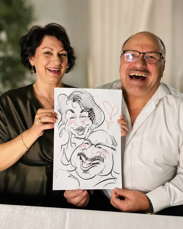 Doi invitați care râd cu caricatura lor în mâini